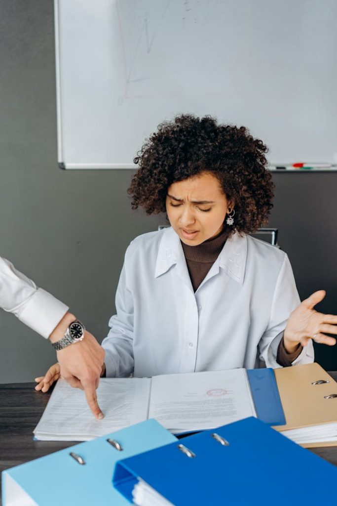 Young woman at office desk overwhelmed by paperwork, highlighting workplace stress.